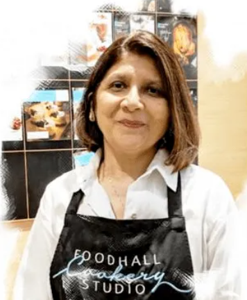 Person wearing a black apron with 'Goodhall Cookery Studio' text in an indoor setting.